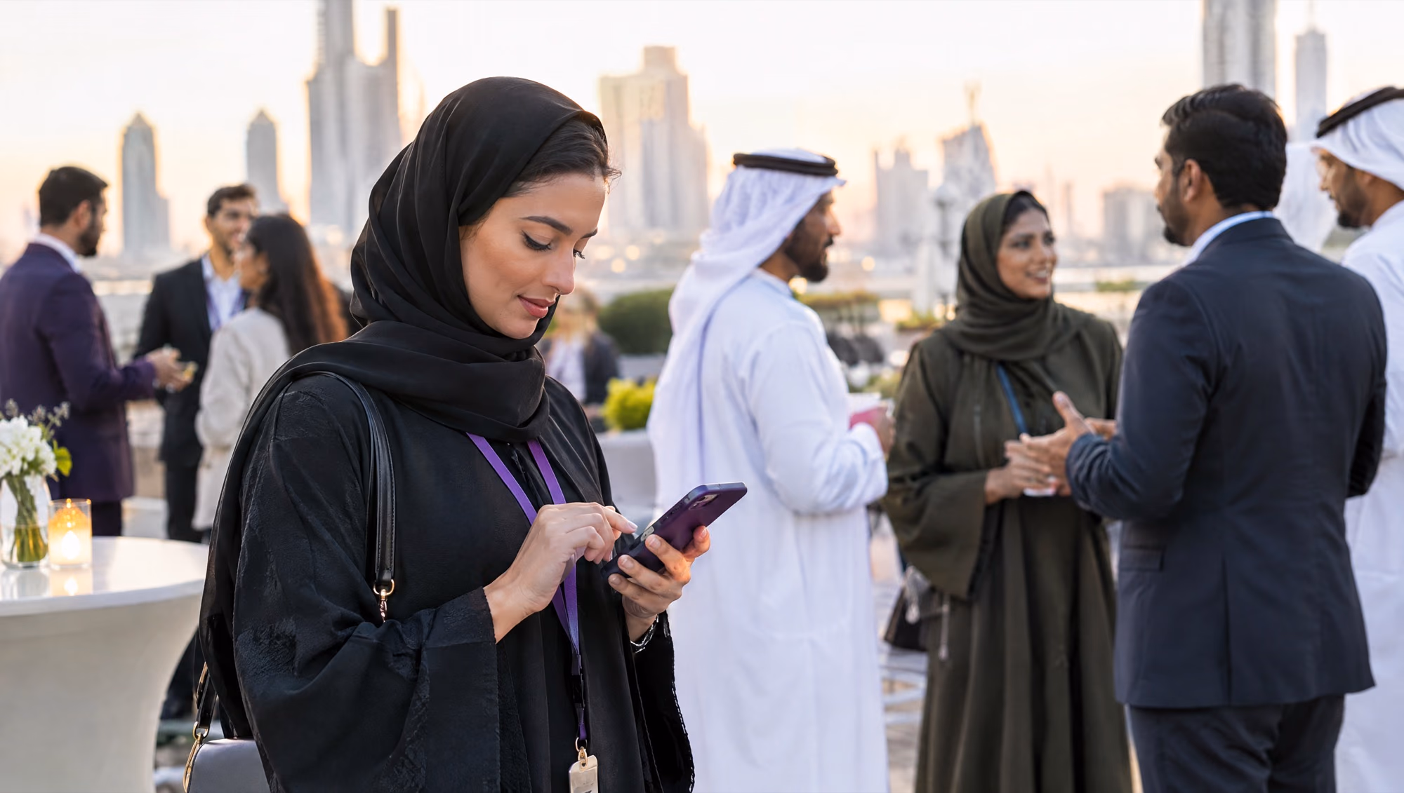 A woman saving a new contact on her phone at a business networking evening, people talking in small groups behind her